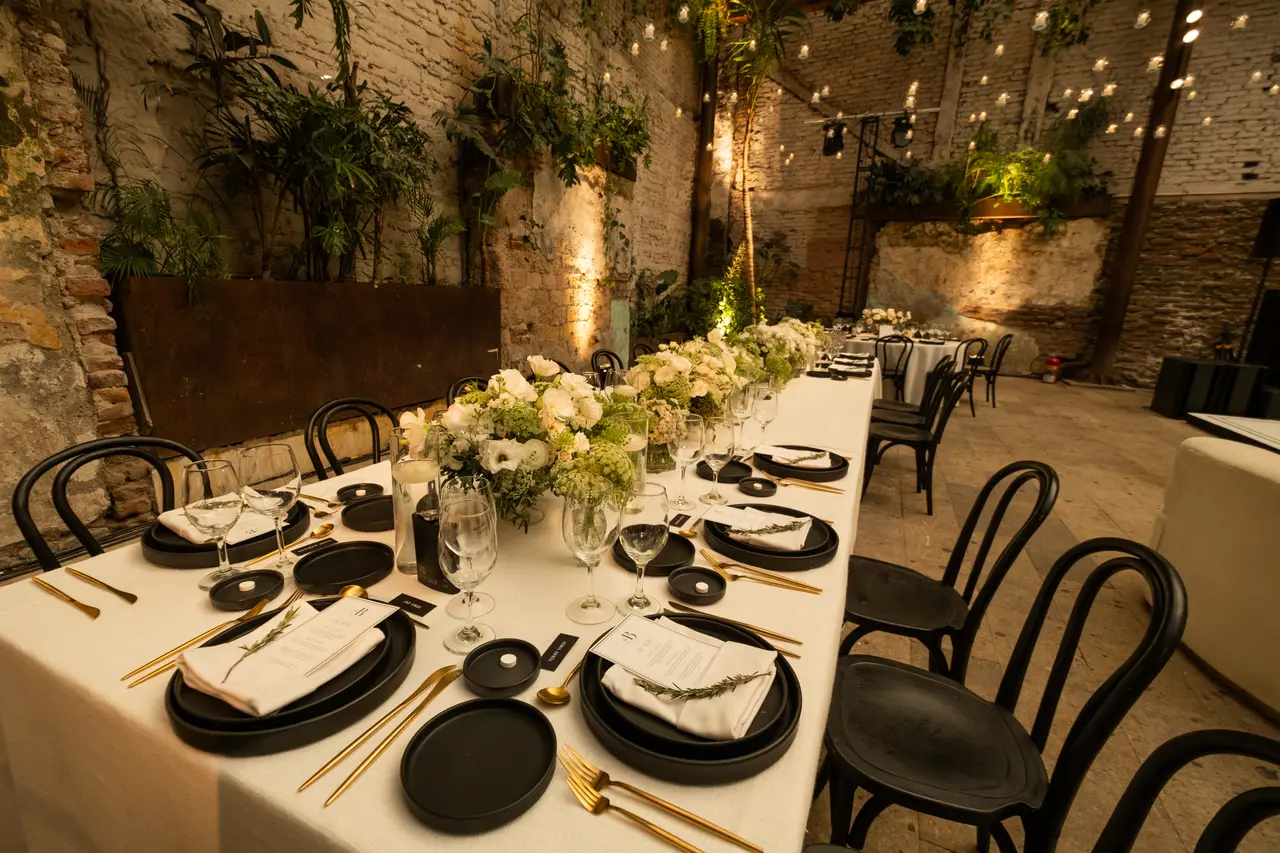 Una mesa larga con guirnaldas de luces y centros de flores blancas