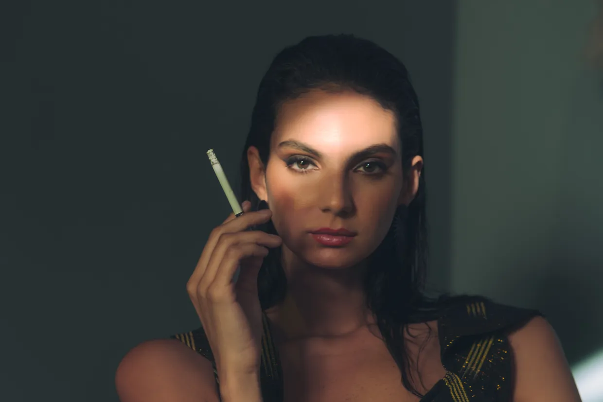 Retrato de frente contra una pared lisa, con la luz cruzando media cara y la otra media dentro de la sombra