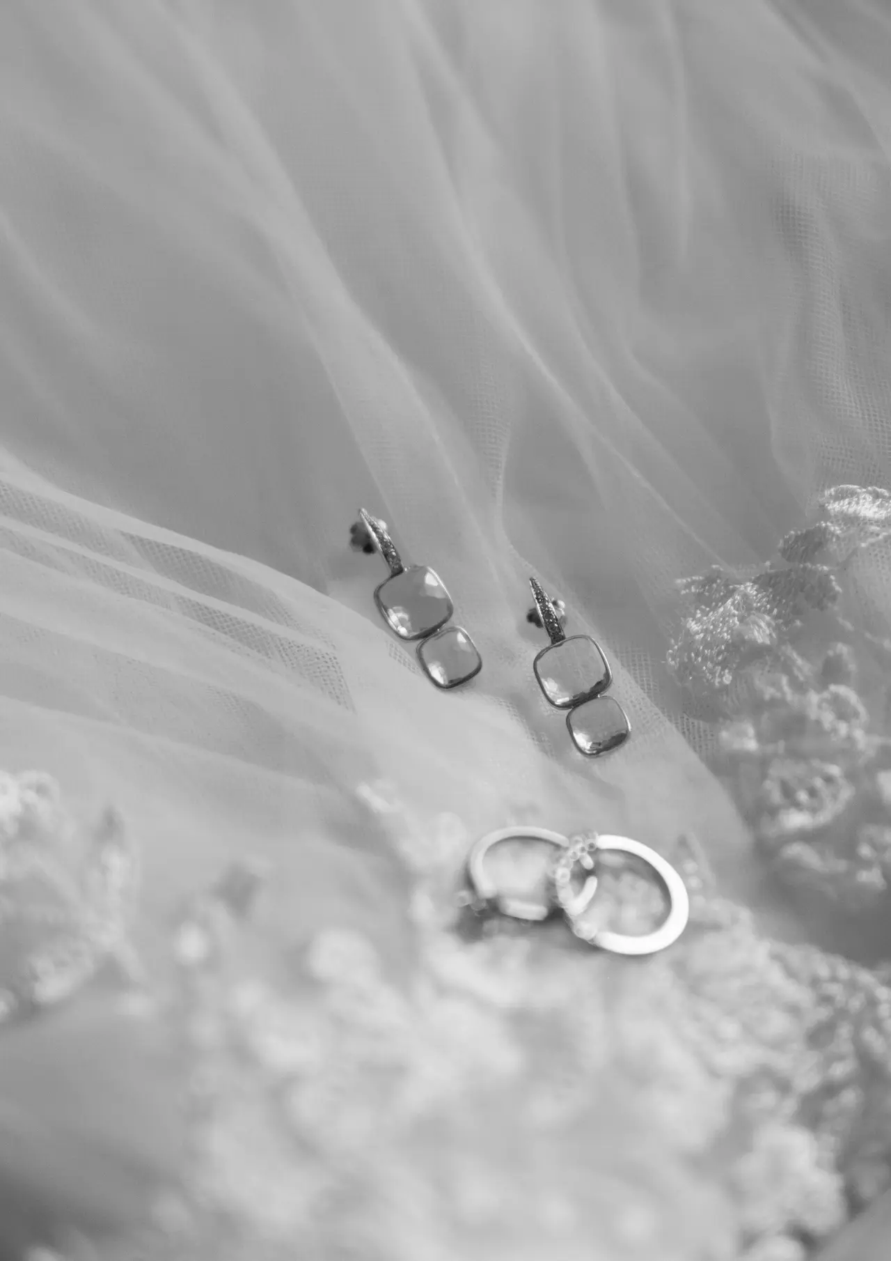 Los aretes y las alianzas apoyados sobre el tul del vestido