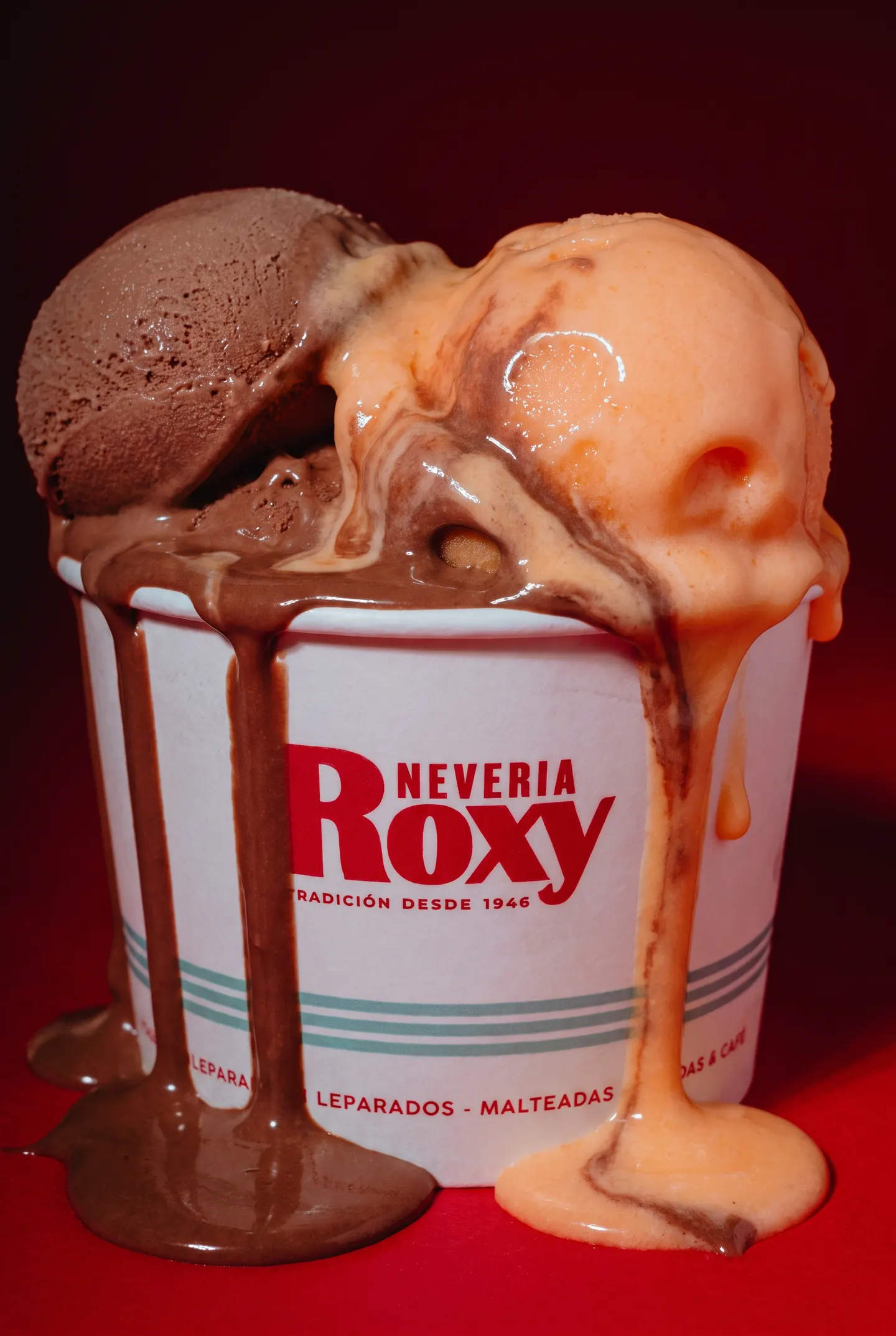 Un bote de Nevería Roxy con dos bolas derritiéndose sobre el fondo rojo de la marca