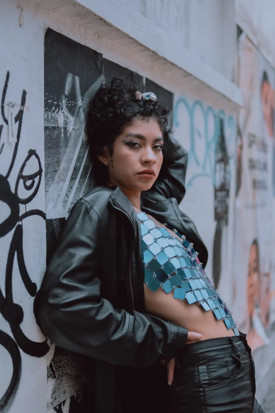 Retrato de cuerpo entero contra una pared empapelada de carteles y pintas