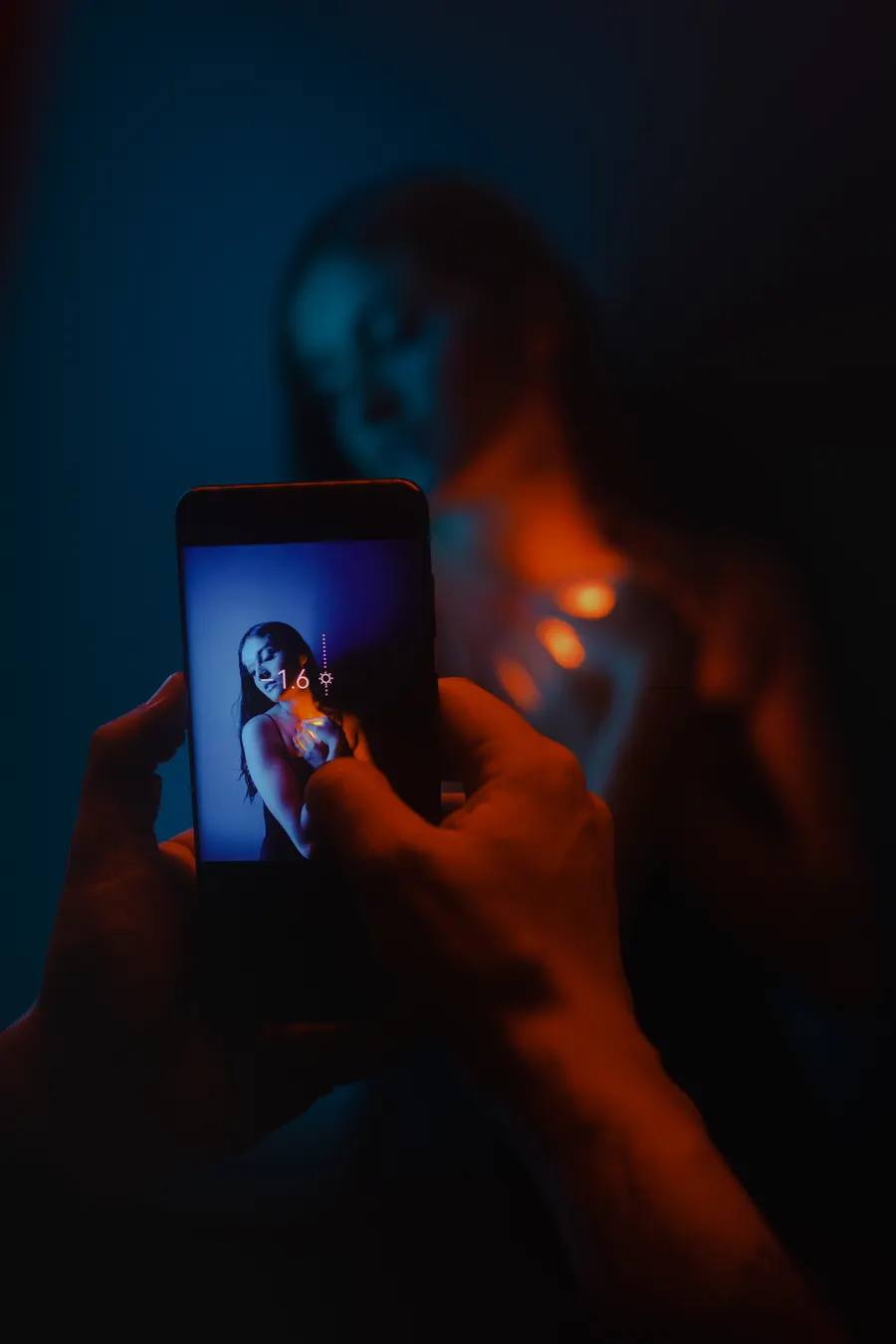Una mano sostiene un teléfono que graba a alguien bajo luz roja