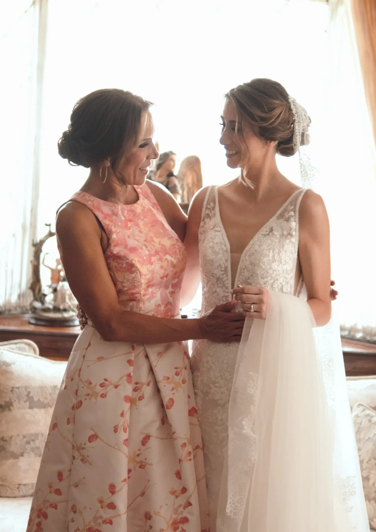 La madre y la novia brindan juntas frente al ventanal, a contraluz