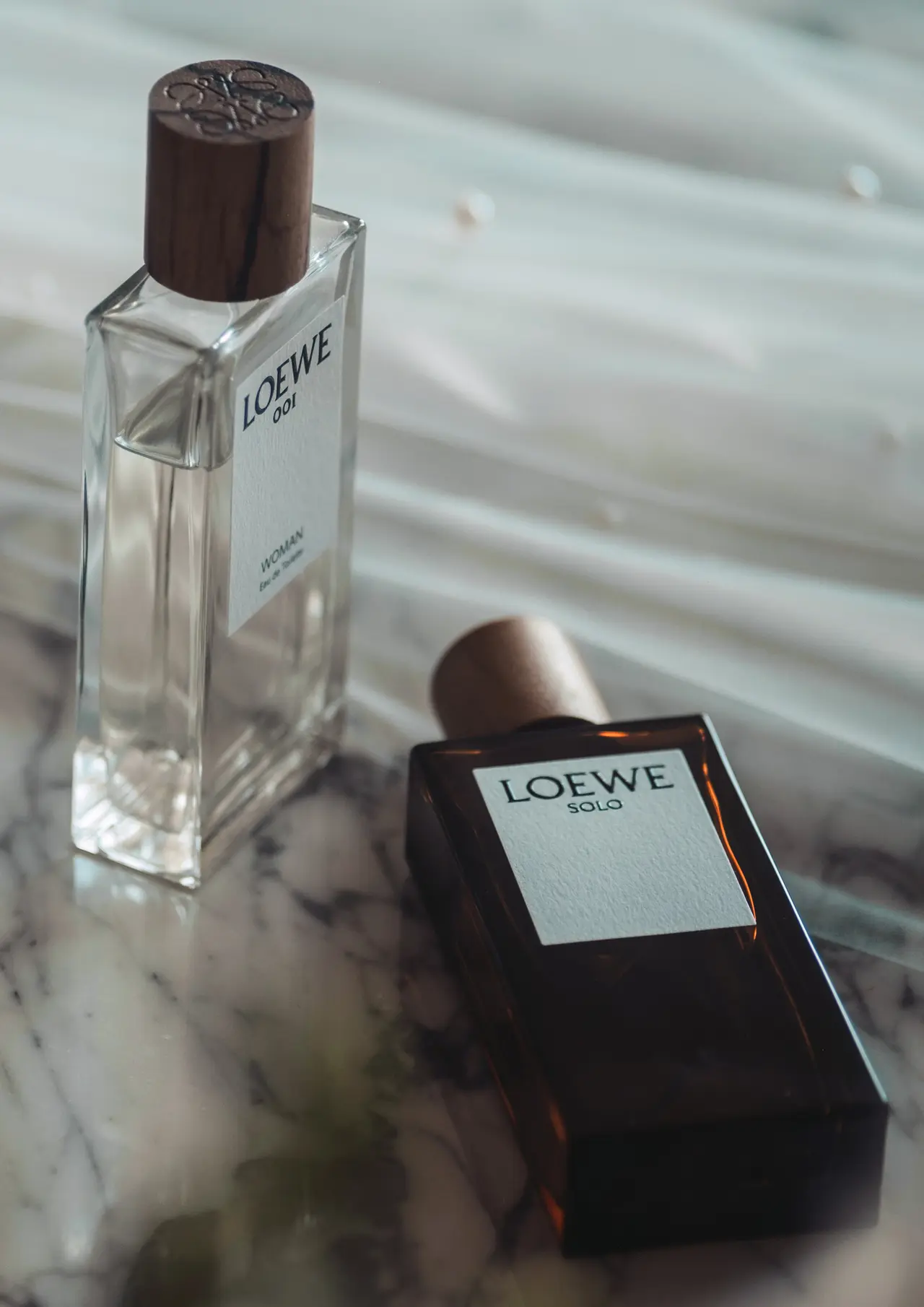 Un frasco de perfume sobre su caja, junto al tul del vestido