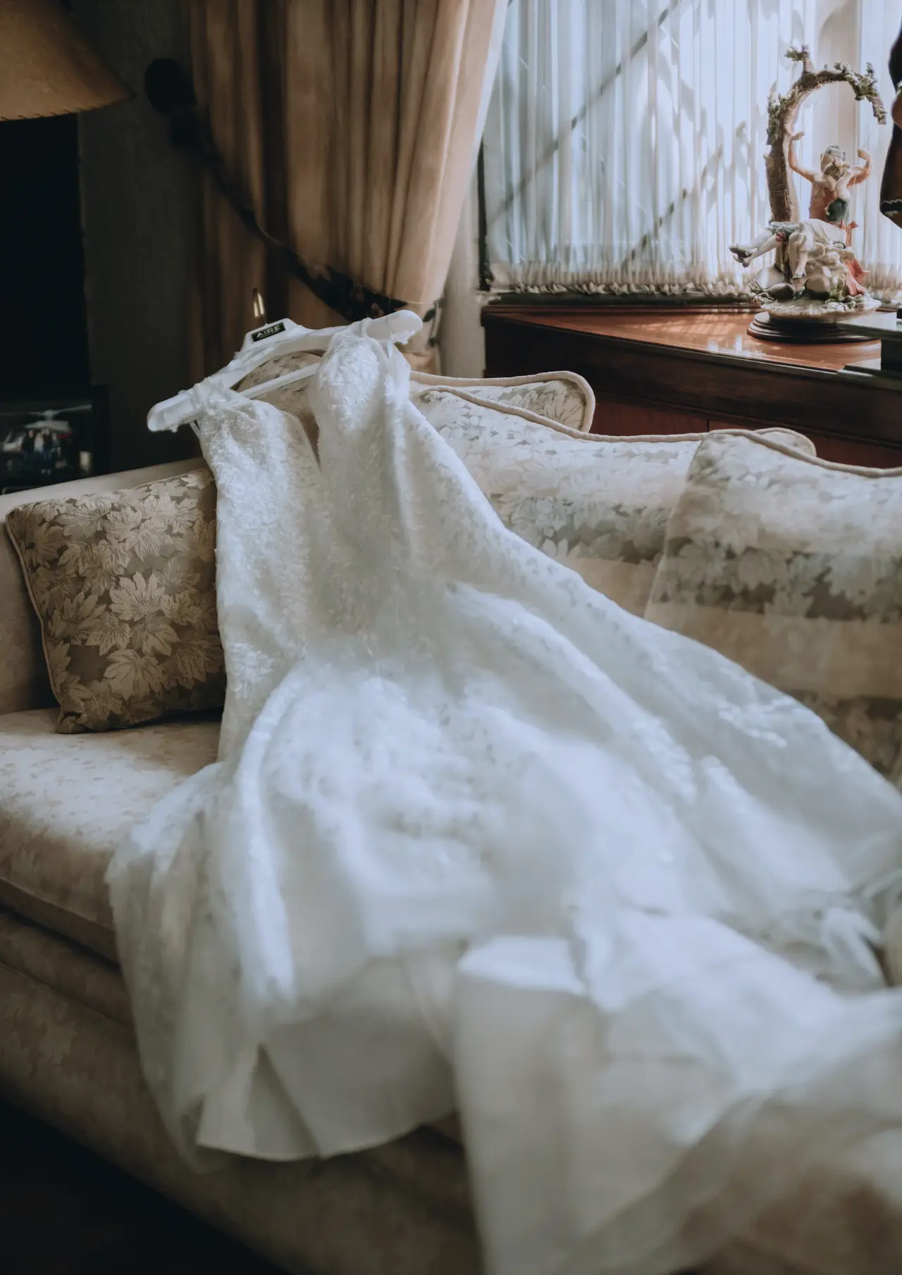 El vestido de novia tendido sobre un sofá junto a la ventana