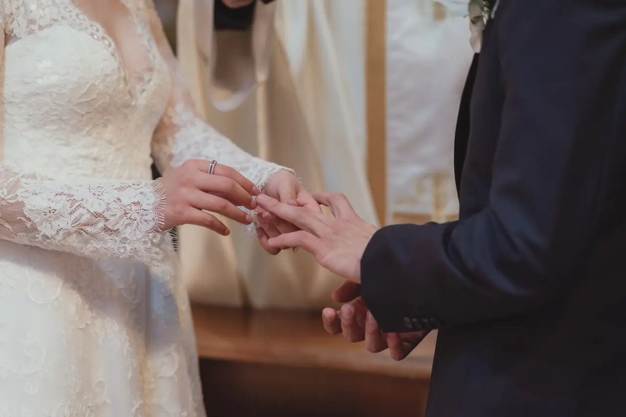 Las manos de los novios en el momento en que el anillo entra en el dedo