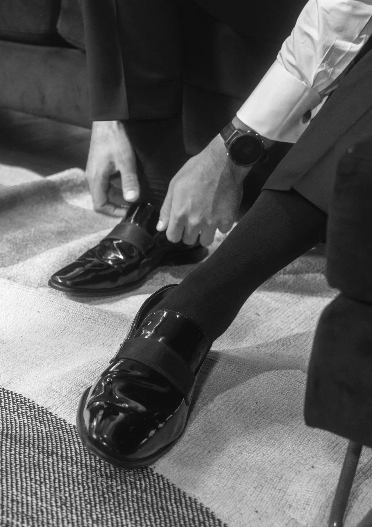 Unas manos atan los zapatos del novio, en blanco y negro